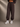 Person wearing Coco brown sweatpants and white sneakers on a neutral background